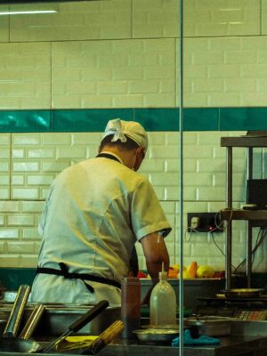 A chef in a commercial kitchen is focused on preparing fresh ingredients for a meal.