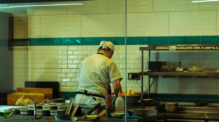A chef in a commercial kitchen is focused on preparing fresh ingredients for a meal.