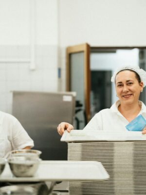 Friendly cafeteria staff working together in a kitchen, showcasing teamwork and service.